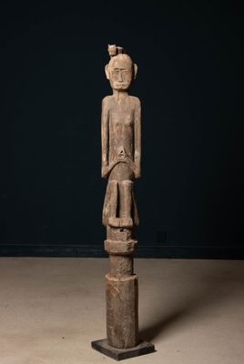 une statue en bois représentant une femme debout sur un piédestal