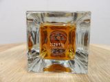 a small square glass candle holder with a label on it