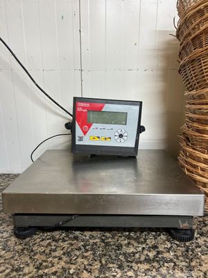 une photo représentant une balance posée sur un comptoir, avec un panier en osier en arrière-plan