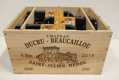 des bouteilles de vin dans une caisse en bois posée sur une surface blanche