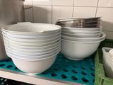 many bowls and pans stacked on a shelf in a kitchen