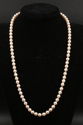 a white pearl necklace on a black mannequin