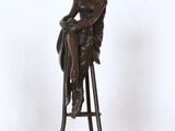 statue représentant une femme assise sur un tabouret, coiffée d'un chapeau