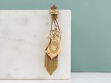 a gold clock hanging from a chain on a marble block