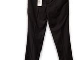 Le pantalon noir est suspendu à un cintre accroché à un mur blanc.