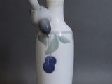 un vase blanc surmonté d'un oiseau bleu