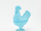 poulet en verre bleu sur un socle, sur fond blanc