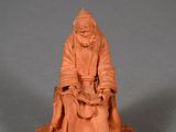 a small clay figurine of an old man sitting on a chair