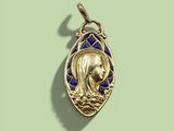 an image of a gold pendant with a picture of a woman in a boat