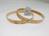 deux bracelets en or posés sur une surface blanche, accompagnés d'une étiquette de prix