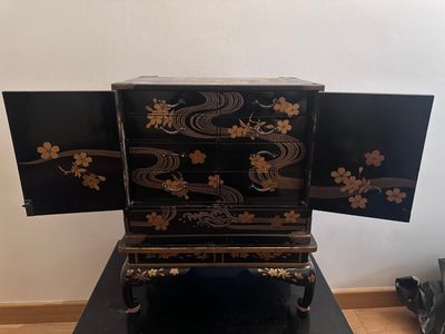a black and gold chest of drawers on a black table