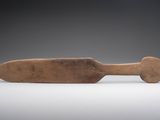 une vieille pagaie en bois avec un manche en bois posée sur une surface blanche