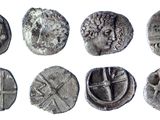 a close up of a group of ancient coins on a white surface