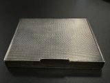 an old silver cigarette case sitting on top of a black table