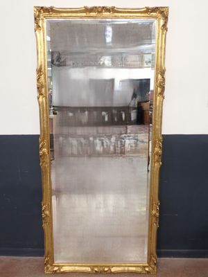 une photo représentant un grand miroir encadré d'or dans une pièce