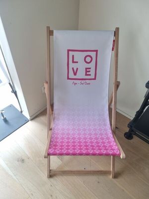 a pink and white beach chair sitting on a hard wood floor