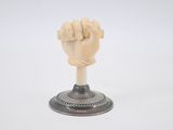 une petite statue représentant un poing, posée sur un socle