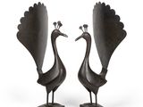 une paire de sculptures en bronze représentant des paons, posées sur des socles, sur fond blanc
