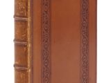un vieux livre à la couverture en cuir marron posé sur une surface blanche