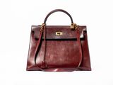 the brown leather handbag is sitting on a white surface