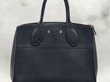 a black leather handbag sitting on top of a white table