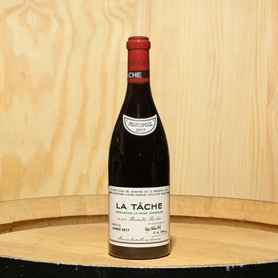 a bottle of wine sitting on top of a barrel