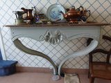 une petite table sur laquelle se trouve un vase, avec une chaise devant