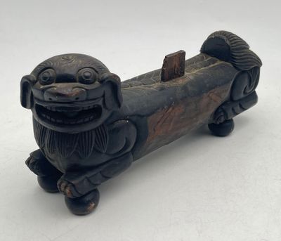 an antique carved dog figurine on wheels on a white surface