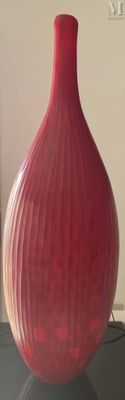 un vase rouge posé sur une table noire dans un salon
