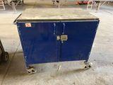 une armoire bleue à deux portes, montée sur roulettes, dans une pièce