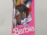 une poupée dans la boîte d'une poupée Barbie, tenant une batte de baseball