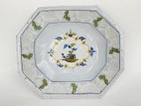 une assiette ornée d'un oiseau, posée sur une table blanche