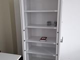 a white cabinet with a door open next to a desk