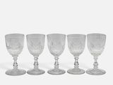 four clear wine glasses sitting on top of each other on a white surface