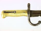 a gold colored sword with a black handle on a white surface