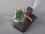 a close up of a ring with a green stone surrounded by diamonds