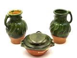 trois vases verts posés les uns à côté des autres sur une surface blanche