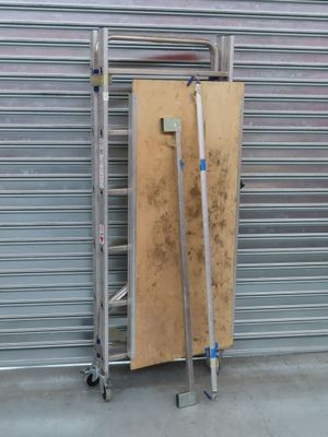 un chariot métallique surmonté d'une planche en bois, devant une porte de garage