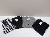 trois paires de chemises et de pantalons noirs et blancs posées sur une surface blanche
