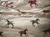 a blanket with horses printed on it on a bed