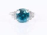 a blue diamond and diamond ring on a white background