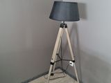 une lampe posée sur un trépied en bois dans une pièce