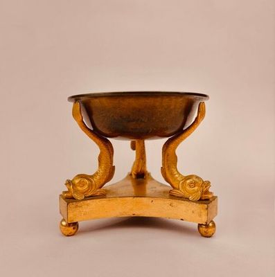 an antique brass footed bowl on a stand on a white background