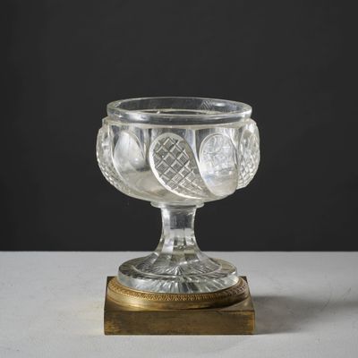 un bol en verre avec un socle doré posé sur une table