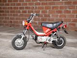 a small red motorcycle parked in front of a brick wall