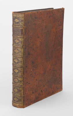 un vieux livre à la couverture brune posé sur une surface blanche