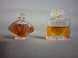 two bottles of perfume sitting next to each other on a table