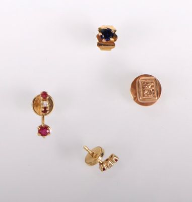 trois paires de boucles d'oreilles en or et une bague posées sur un fond blanc