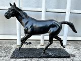 a statue of a black horse running on a black base