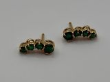 a pair of gold earrings with emerald stones